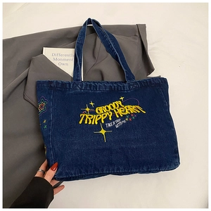 Detailed embroidery of GROOVY TRIPPY HEART on dark blue denim tote bag surface