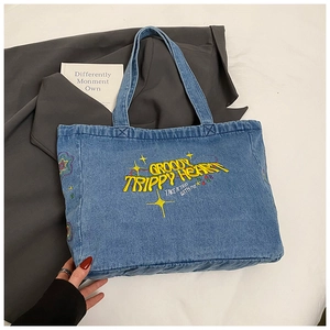 Detail of blue denim tote bag featuring yellow Groovy Trippy Heart embroidery