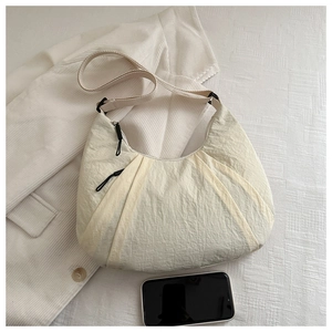 Detail of a creamy beige pleated crossbody bag made of textured scratch-resistant nylon