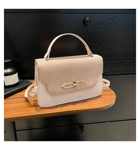 Detail of a dual-tone woven handbag with creamy leather finish and gold metallic buckle lock