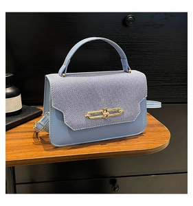 Detail of light blue crossbody bag with denim flap and golden chain metal buckle