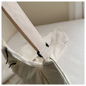 Detail of woven strap with black buckles on a minimalist cream nylon tote bag