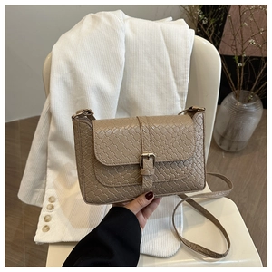 Close-up of beige woven texture crossbody bag with elegant buckle closure on a chair