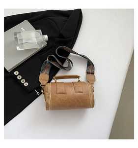 Detailed view of vintage brown cylinder bag with wide ethnic style shoulder strap