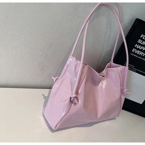 Detail of pink glossy tote bag showing the stylish knotted shoulder strap connector