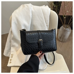 Close-up of black woven leather texture and golden metal buckle on a shoulder bag