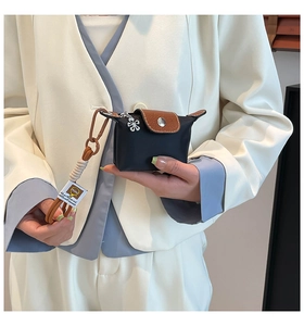 Detailopname van een nylon mini-tas met lederen flap en een decoratieve madeliefje hanger