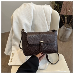 Detail of dark brown woven texture shoulder bag with retro gold buckle and sleek PU leather