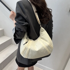 Minimalist cream crescent tote bag with adjustable strap shown on model's shoulder