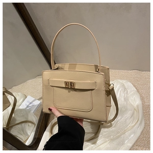Detailed close-up of beige crossbody tote bag with cross-grain texture and gold lock buckle
