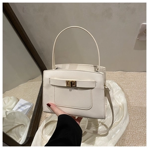 Detail of off-white Saffiano leather tote bag featuring golden twist lock and twin handles