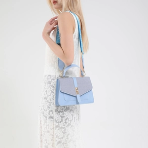 Sac bandoulière bleu clair avec rabat à carreaux et large sangle sur un mannequin femme
