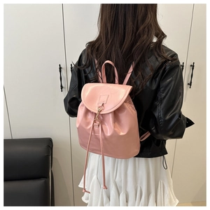 Detail of pink mini faux leather backpack showing drawstring closure and gold buckle
