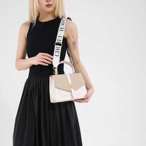 Sac à bandoulière en cuir blanc avec large sangle CHCH et fermoir doré, porté par un mannequin