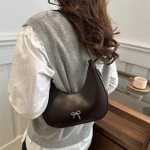 Sac hobo marron avec nœud argenté porté par un mannequin, style tendance pour 2025