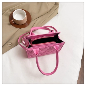 Detailed interior of rose pink quilted handbag with zippered compartment and top handles