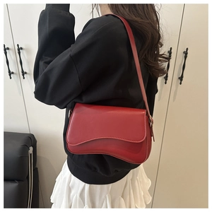 Detail of red irregular wave-shaped flap shoulder bag with matte leather and gold hardware