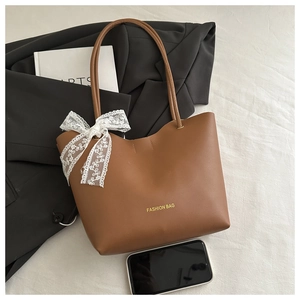 Détail du sac cabas en cuir PU marron avec nœud en dentelle blanche et texte doré chic