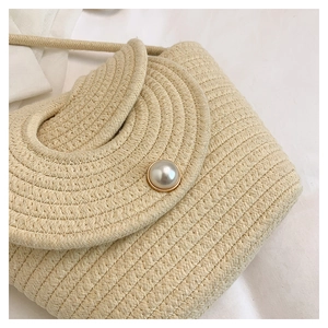 Detailed view of handmade woven beige crossbody bag featuring a large pearl buckle closure