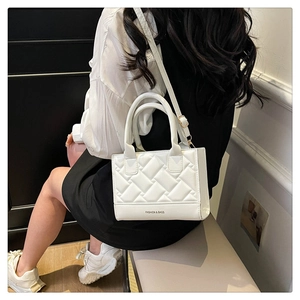 Macro detail of white quilted handbag with Fashion and Bags embossed text and silver hardware