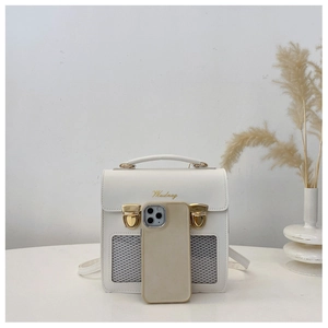Dettaglio dello zaino bianco con logo oro, fibbie vintage e finestra in mesh sul tavolo