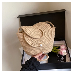 Detailed close-up of woven bucket bag featuring spiral flap and decorative large pearl