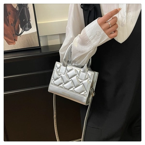 Detail of silver metallic handbag featuring geometric texture and elegant crossbody strap