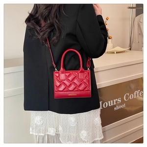 Detail of red quilted woven handbag featuring gold FASHION & BAGS lettering and hardware