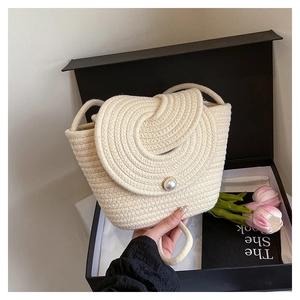 Detail of hand-woven off-white bucket bag featuring a central pearl buckle on a spiral flap