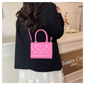Macro shot of bright pink crossbody bag with woven texture and gold fashion lettering