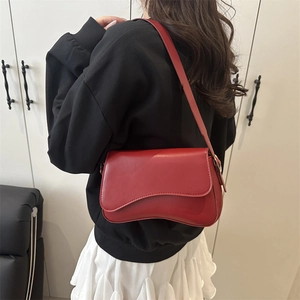 Minimalist deep red shoulder bag with curved base and adjustable strap for women