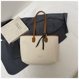 Chic cream tote bag with brown trim, featuring a decorative scarf and tennis racket charm