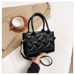 Detail view of black quilted crossbody bag with gold fashion lettering and thin strap
