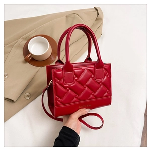 Detail of red quilted leather handbag showing golden text and diamond pattern texture