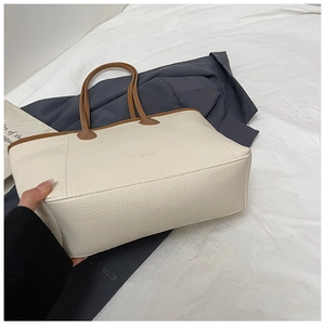 Detail of the litchi texture leather tote bag in beige with contrast brown trim and engraving