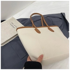 Detailed close-up of cream lychee texture tote bag with brown trim and embossed logo