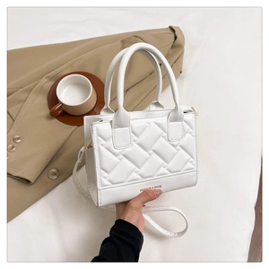 Close-up of elegant quilted white handbag with top handles and cross-body strap detail