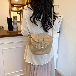Handmade woven crossbody bag with pearl closure shown on model in cafe setting