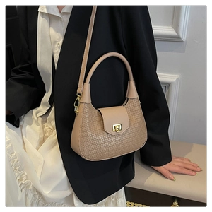 Detail of woven crescent bag with golden twist lock and dual straps on model