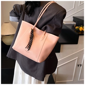 Close-up of light pink lychee texture tote bag with tassel pendant and fashion logo