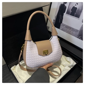 Detailed shot of white woven crescent bag with beige leather trim and gold metal lock in gift box