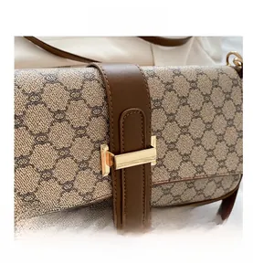 Gros plan sur toile monogramme vintage avec boucle dorée et détails en cuir brun
