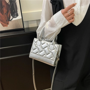 Silver quilted mini tote bag with woven texture and top handle shown in a lifestyle setting
