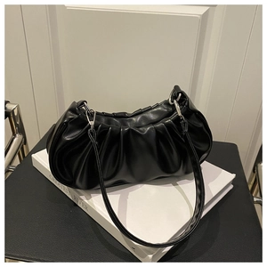 Detail of the black ruched handbag with silver zipper and glossy leather texture