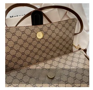 Gros plan du fermoir magnétique doré et du motif classique du sac baguette marron