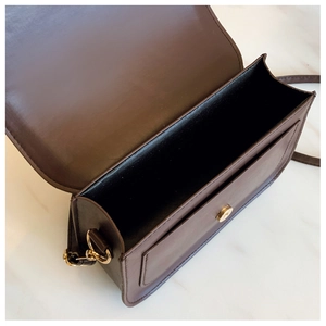 Detail view of coffee brown crossbody bag showing spacious interior and golden magnetic buckle