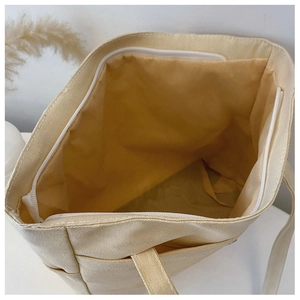 Internal structure of beige canvas tote bag showing zipper closure and inner pocket