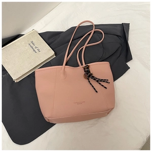 Close-up of pink lychee grain tote bag with fashion lettering and striped tassel detail