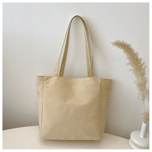 Detail of beige canvas tote bag showing side pockets and thick fabric texture
