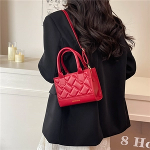 Elegant red quilted square handbag with adjustable strap shown in a modern interior setting